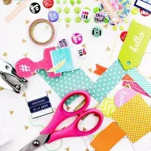 Scattered craft supplies, including paper, scissors, and stickers