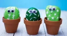 3 rocks painted like cactus with googly eyes in a pot