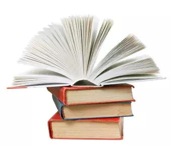 pile of books with top book opened up to pages fanned out