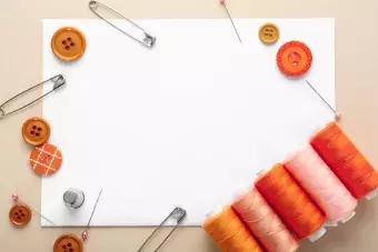 craft supplies that include orange buttons and thread