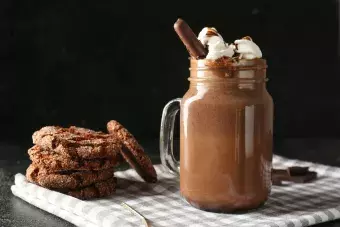 Mason jar of hot chocolate with cookies on dark background