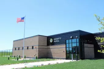 Sheriff Patrol Headquarters building with flag flying in foreground.