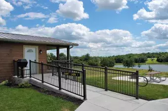 A side view of the cabin with grill, ramp, firepit and picnic table.