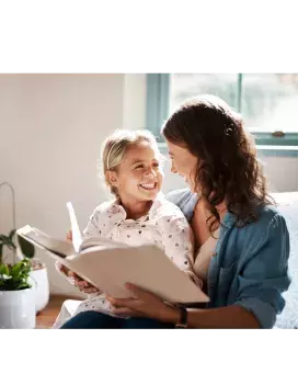 Photo of adult woman and young girl reading a book together