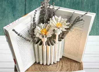an old book made into a flower vase by cutting pages 