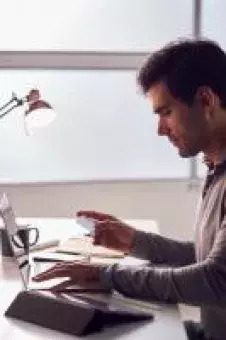 This is a man holding a credit card while sitting at a laptop computer. 