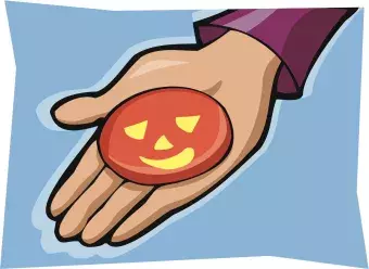 This is a picture of a hand holding a pumpkin cookie