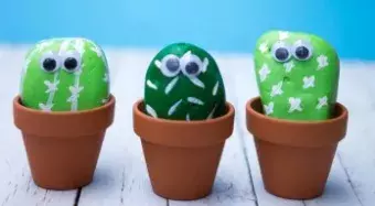 3 rocks painted like cactus with googly eyes in a pot