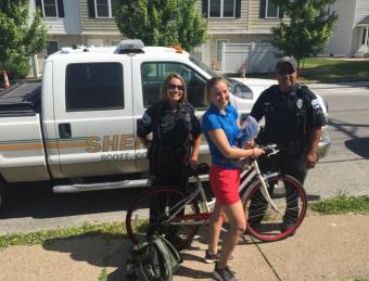 Police officers with a girl on a bike.