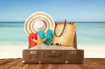 Suitcase filled with sand and beach gear.