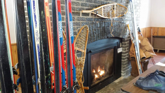 Snow skies propped up being dried next to a fireplace.