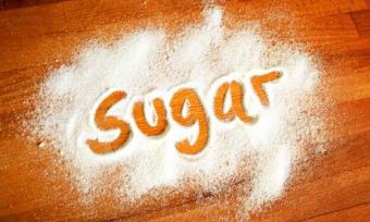 The word 'Sugar' spelt out in spilled sugar.