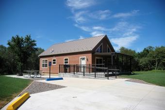 Full view of cabin with parking spaces and patio with picnic tables and fire ring.