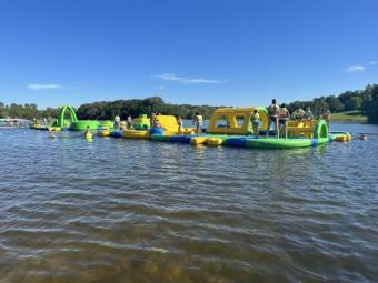 Several children running and playing in lifejackets on the inflatable waterpark (Wibit).