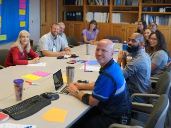 Group of people sitting around a conference table turning and smiling at the camera.