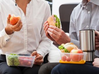 Group of people eating fruit and sandwiches.