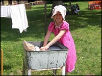 Girl washing cloths in a tub of water.