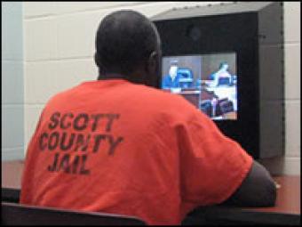 An inmate watching at a monitor for video court.