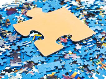 one big piece on pile of disassembled little blue jigsaw puzzles