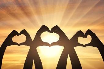 Three pairs of hands show a heart symbol on a sunset background