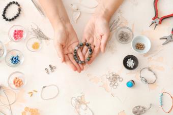 person making beaded bracelet with beads and supplies on the table