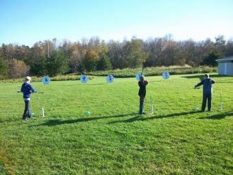 Students lining up bow and arrow on a target.