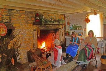 photo of people dress in old time attire sitting by a fire