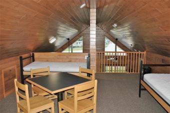 Loft space with four single beds and small table and chairs.