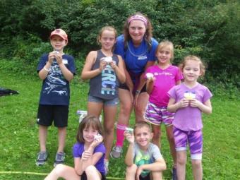 Day Camp Counselor with a group of smiling children outside.