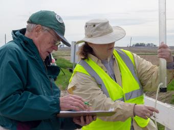 Two people testing a water sample and recording the result.