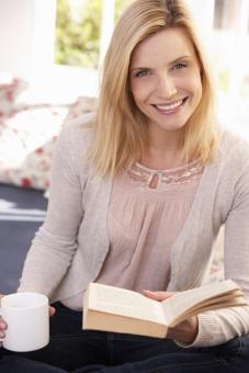 This is a woman with a cup of coffee and a book. 