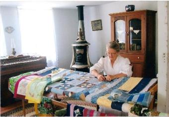 A woman quilting in one of the historic buildings.