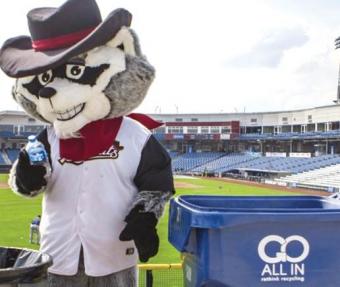 River Bandit mascot holding plastic bottle next to recycling container.