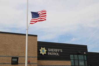 Sheriff Patrol Headquarters building with flag flying in foreground.