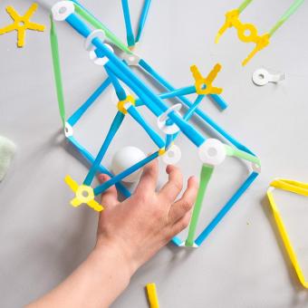 A child's hand building with a Strawbees inventor kit.