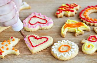 This is a picture of someone decorating homemade shortbread cookies with icing from piping bag