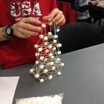 A child building with marshmallows and toothpicks.