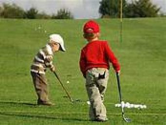 photo of 2 young boys on on golf green