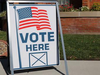 Sign reading "Vote Here"