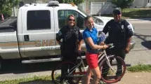 Police officers with a girl on a bike.
