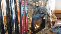 Snow skies propped up being dried next to a fireplace.