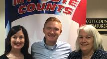 Three voters posing for a selfie in front of the my vote counts poster.