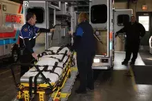 A bariatric rig being loaded into back of ambulance.